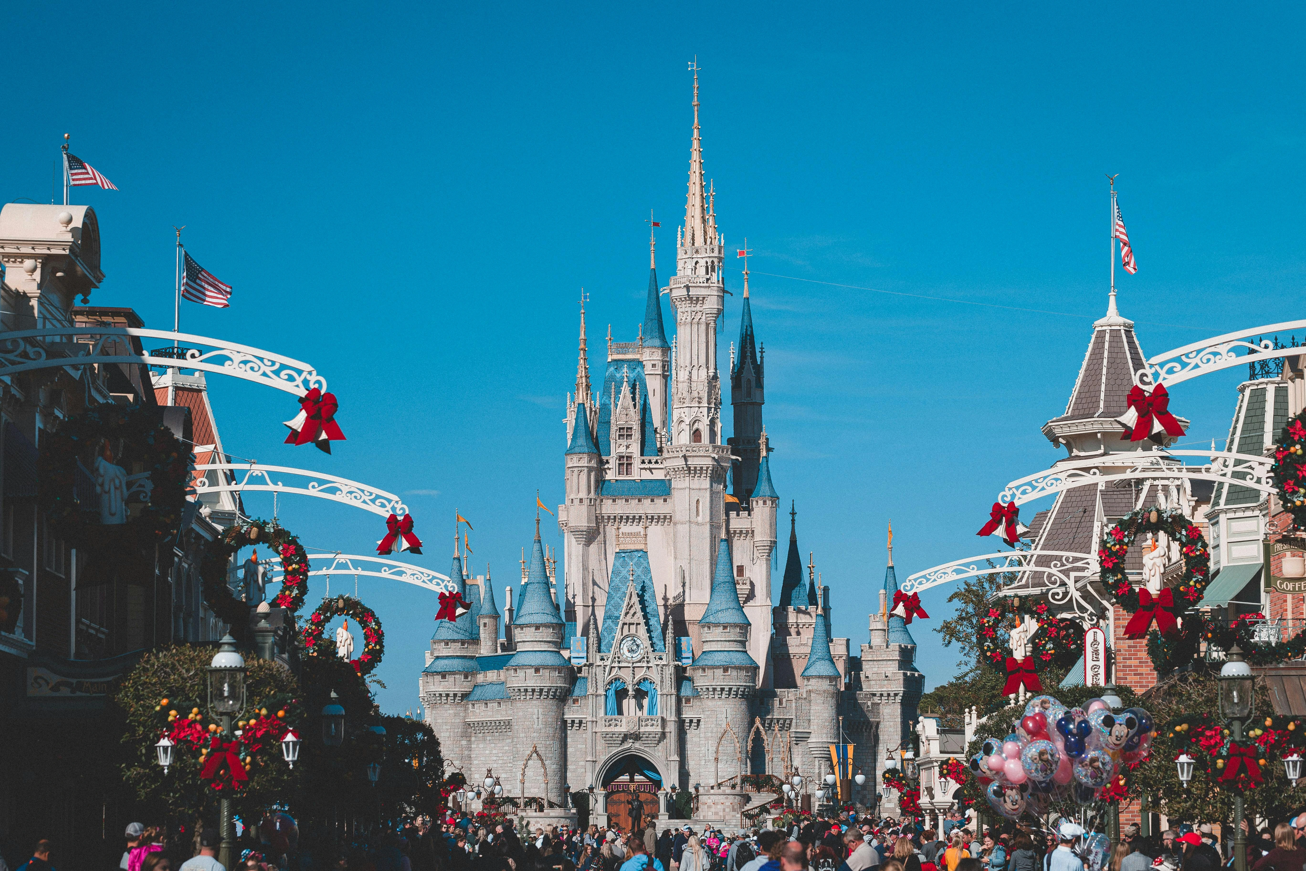 Orlando skyline featuring Disney's iconic Cinderella Castle illuminated at night, with colorful lights reflecting across the water, symbolizing the magical transportation experience to Disney destinations.